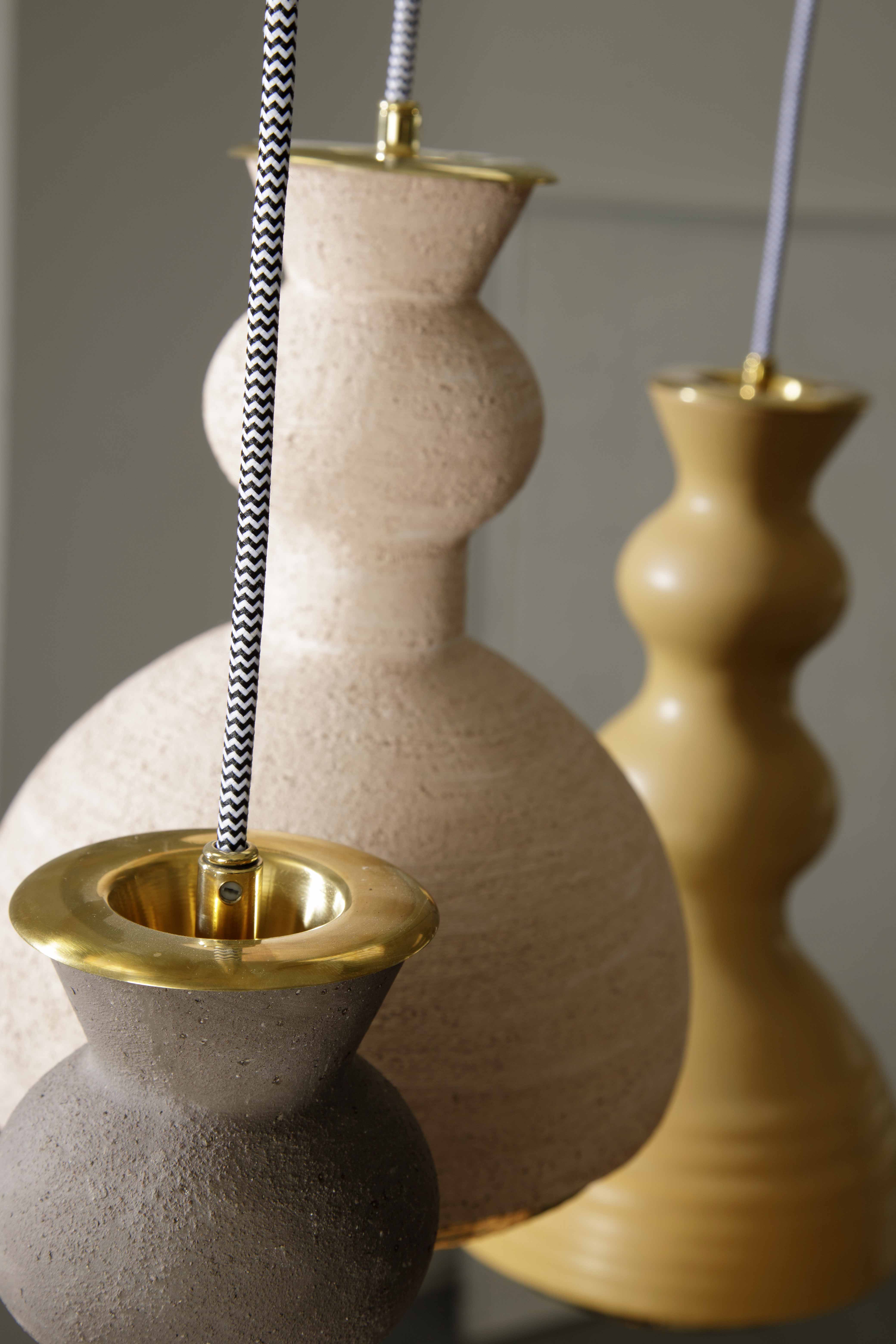 ALLEGRA - Serie di sospensioni in ceramica, colorate con smalti o in terra refrattaria rosata o scura, gli interni sono tutti dorati. In abbinamento; le lampade da tavolo della sua collezione.