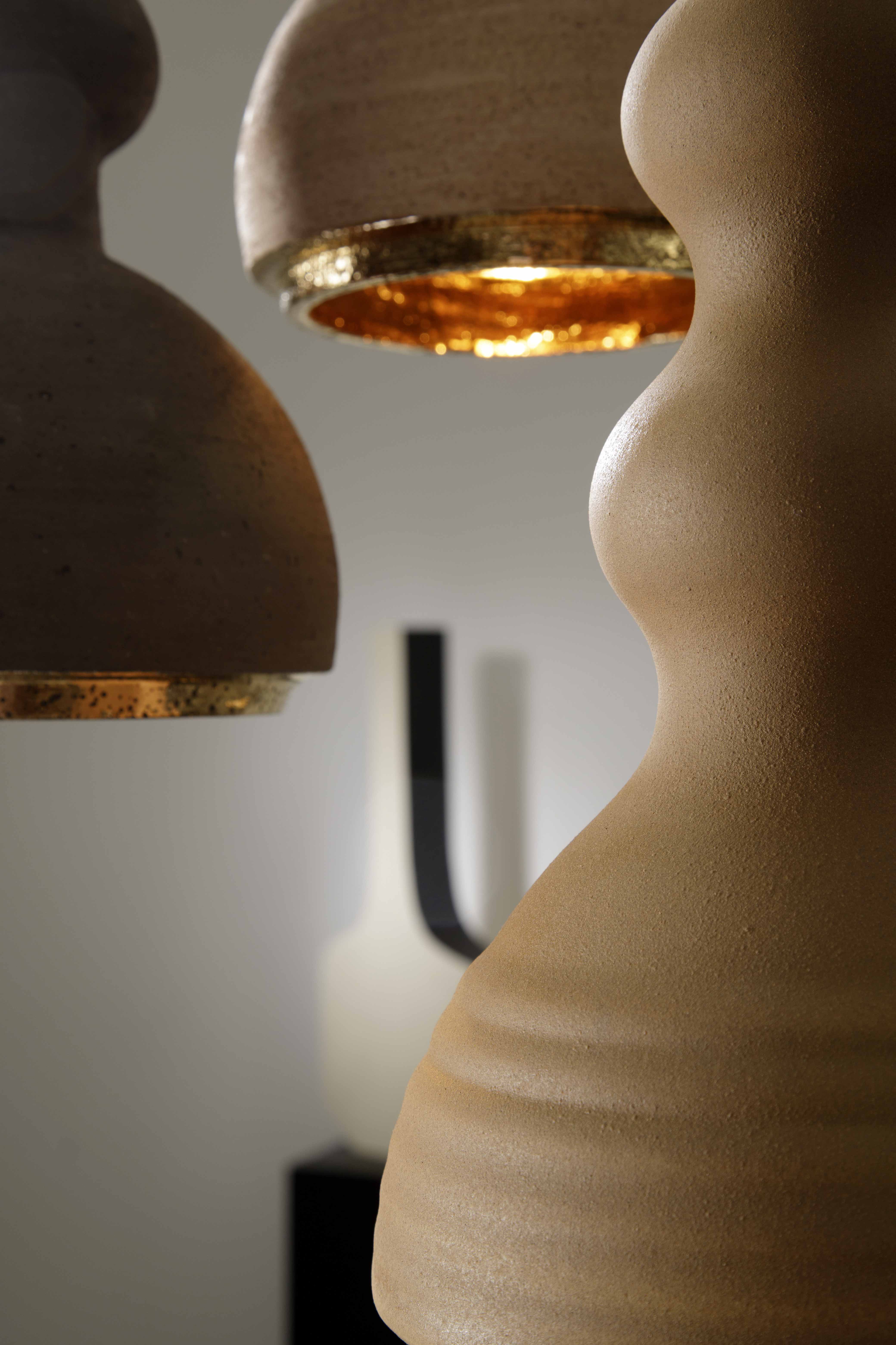 ALLEGRA - Serie di sospensioni in ceramica, colorate con smalti o in terra refrattaria rosata o scura, gli interni sono tutti dorati. In abbinamento; le lampade da tavolo della sua collezione.