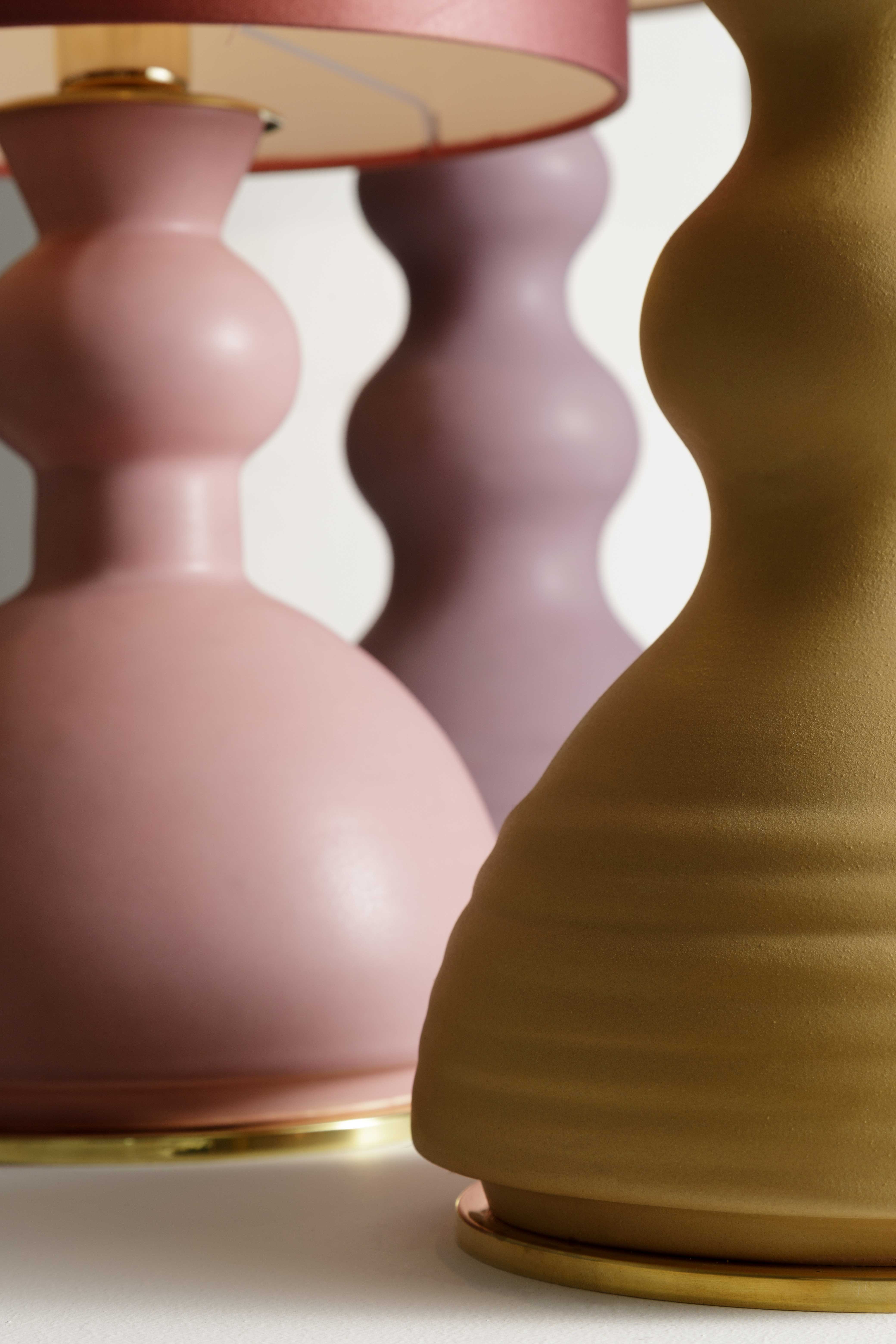 ALLEGRA - Serie di lampade da tavolo in ceramica, colorate con smalti o in terra refrattaria rosata o scura. I paralumi sono in raso colorato o in paglia naturale